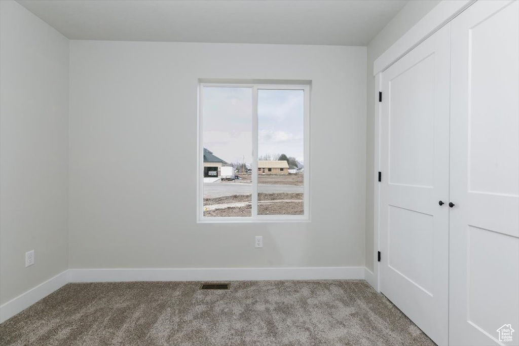 Unfurnished bedroom featuring carpet flooring, baseboards, a closet, and visible vents