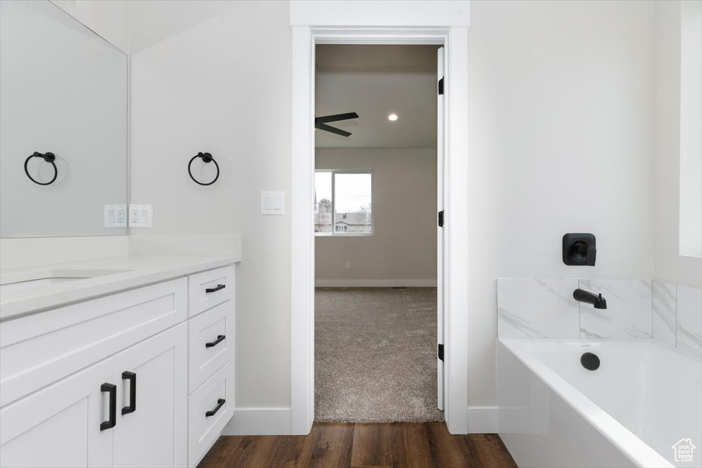 Full bathroom featuring baseboards, a washtub, vanity, and wood finished floors
