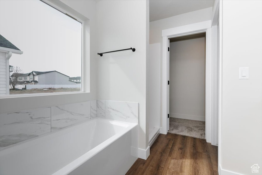 Full bath with baseboards, wood finished floors, and a bath
