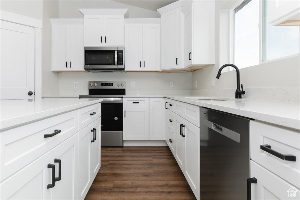Kitchen featuring white cabinetry, a sink, dark wood-style floors, light stone countertops, and appliances with stainless steel finishes