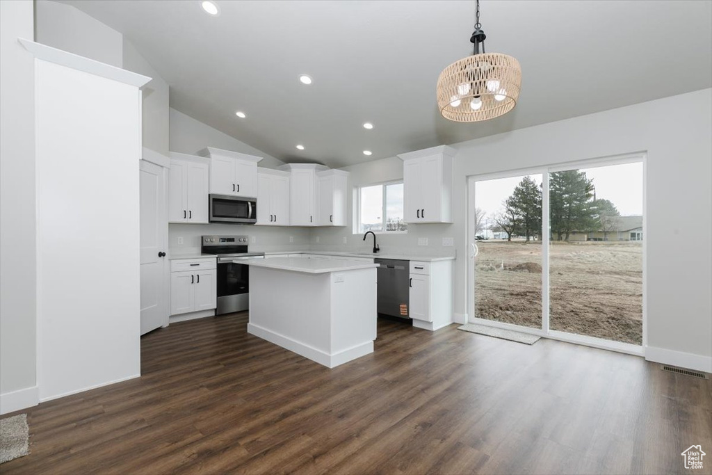 Kitchen featuring dark wood finished floors, appliances with stainless steel finishes, white cabinetry, a sink, and an inviting chandelier