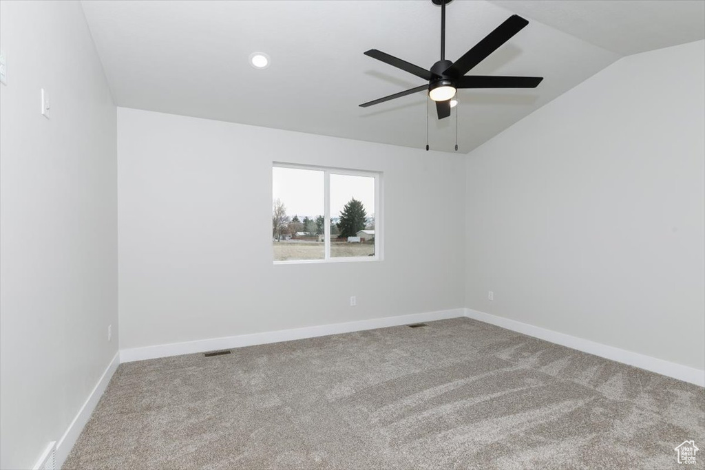 Spare room with carpet floors, baseboards, vaulted ceiling, and ceiling fan