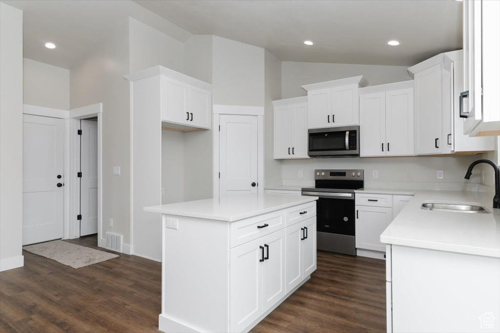 Kitchen featuring a sink, appliances with stainless steel finishes, lofted ceiling, visible vents, and dark wood-type flooring