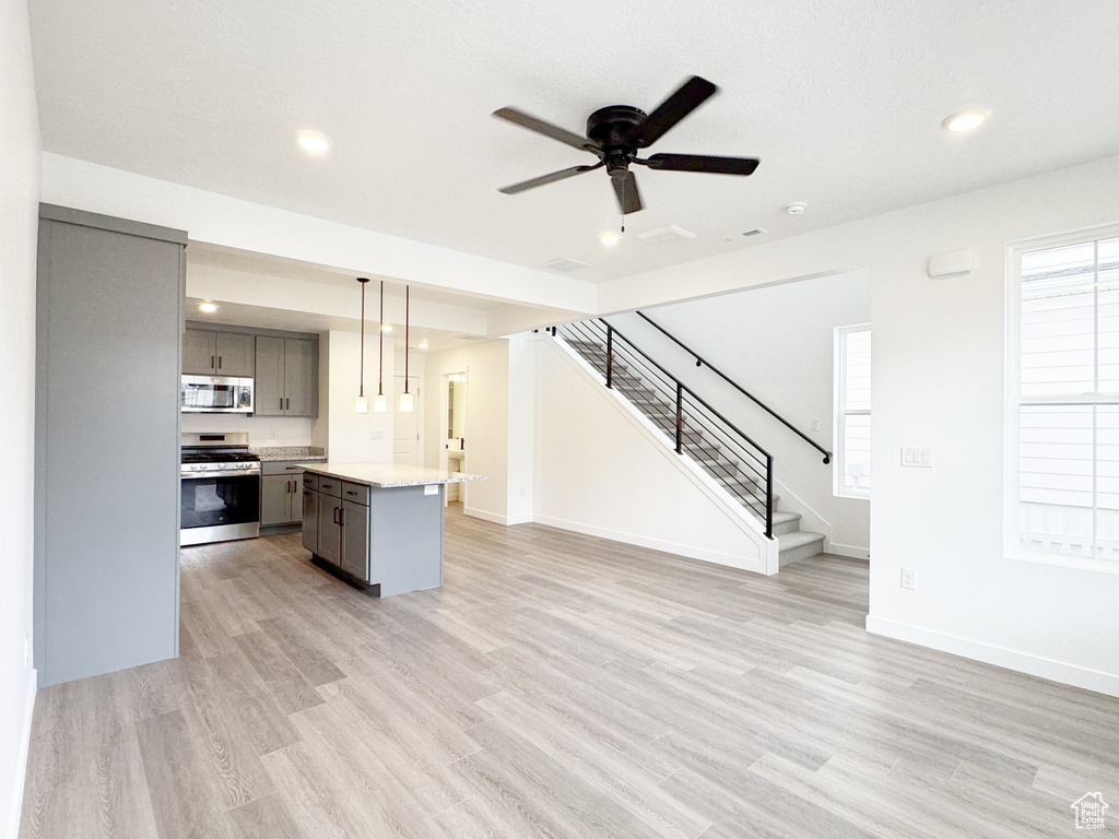 Kitchen with light countertops, gray cabinetry, open floor plan, light wood-type flooring, and stainless steel appliances