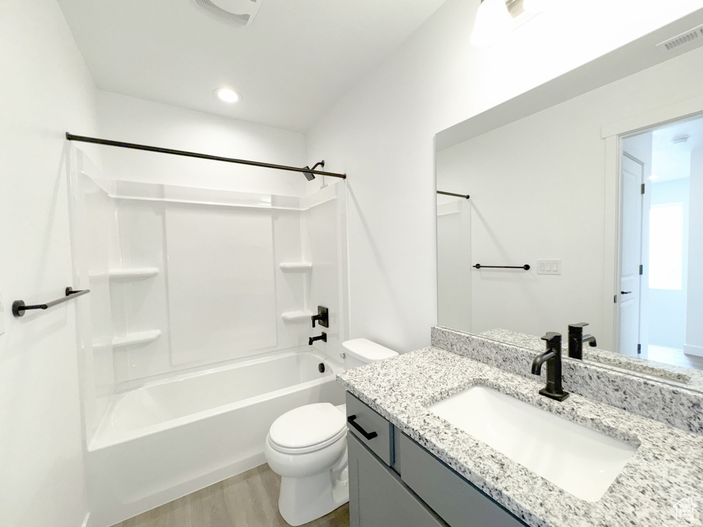 Bathroom featuring toilet, vanity, wood finished floors, tub / shower combination, and visible vents