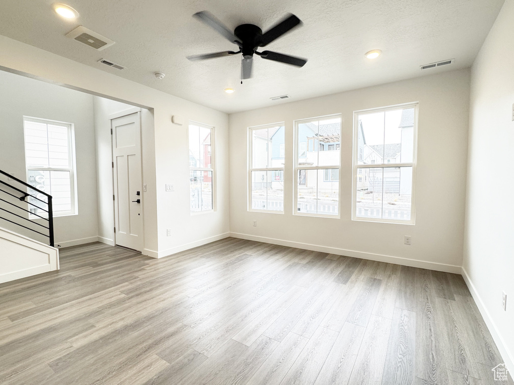 Unfurnished living room with stairs, ceiling fan, visible vents, and wood finished floors