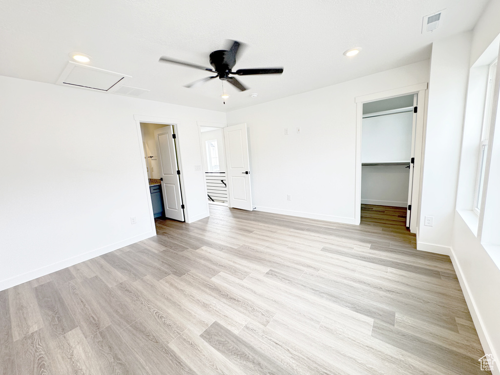 Unfurnished bedroom with baseboards, a spacious closet, visible vents, and light wood-style floors