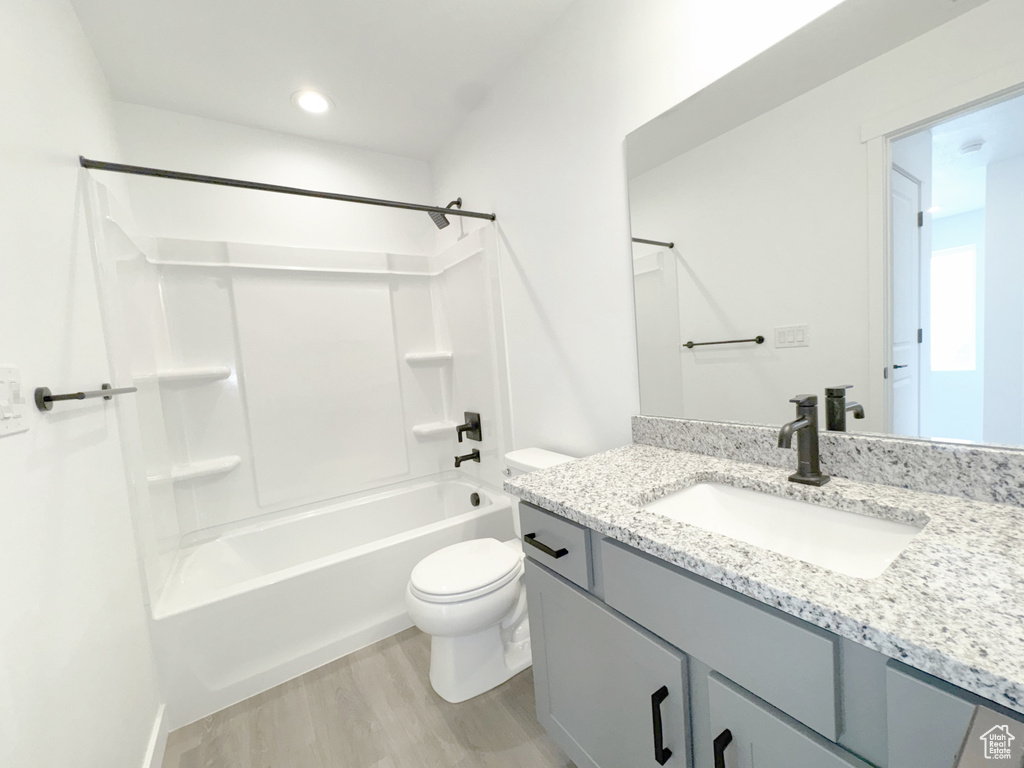 Bathroom featuring toilet, vanity, shower / tub combination, and wood finished floors