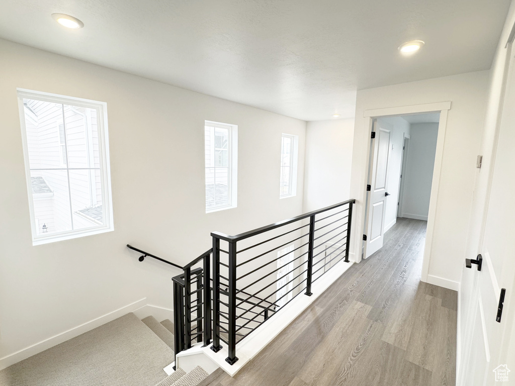 Corridor featuring baseboards, wood finished floors, an upstairs landing, and recessed lighting