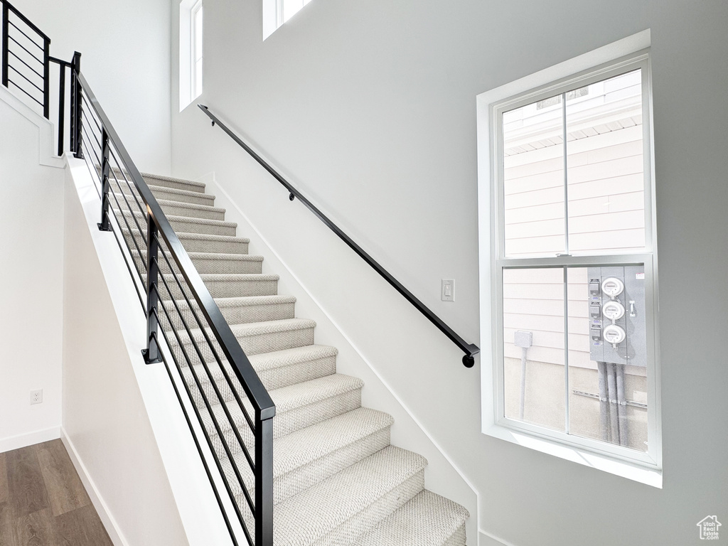 Staircase featuring baseboards, a high ceiling, and wood finished floors