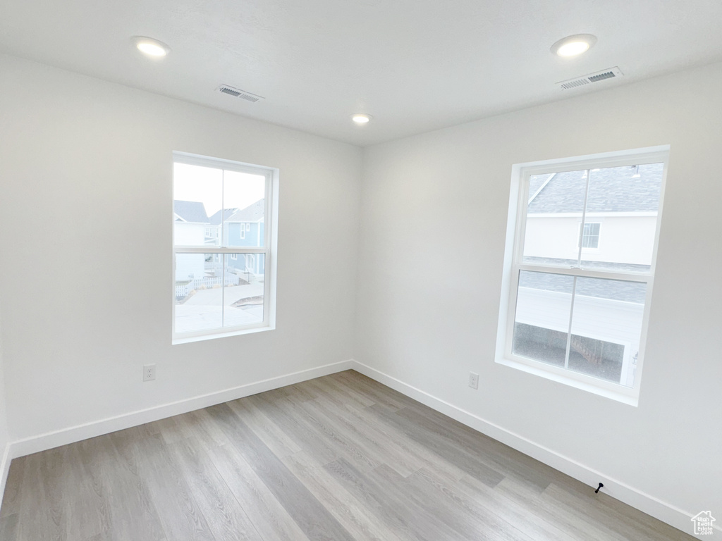 Spare room featuring light wood finished floors, a wealth of natural light, and visible vents