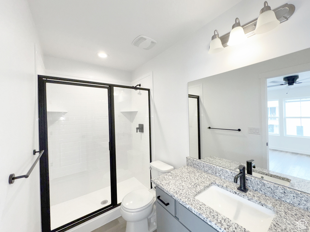 Bathroom featuring a stall shower, toilet, vanity, a ceiling fan, and recessed lighting