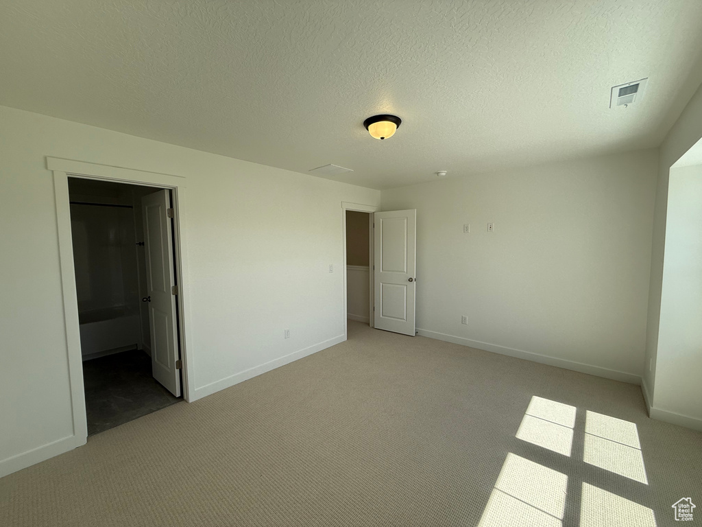 Unfurnished bedroom with light carpet and baseboards