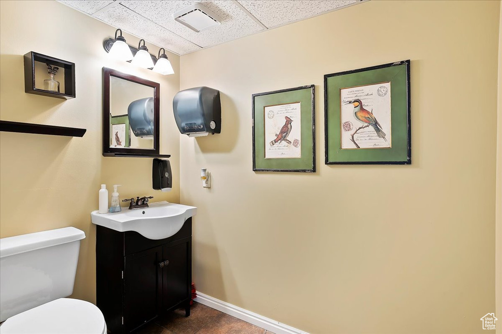 Bathroom with vanity, toilet, baseboards, visible vents, and a paneled ceiling
