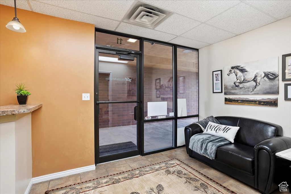 Interior space featuring floor to ceiling windows, a paneled ceiling, baseboards, and visible vents