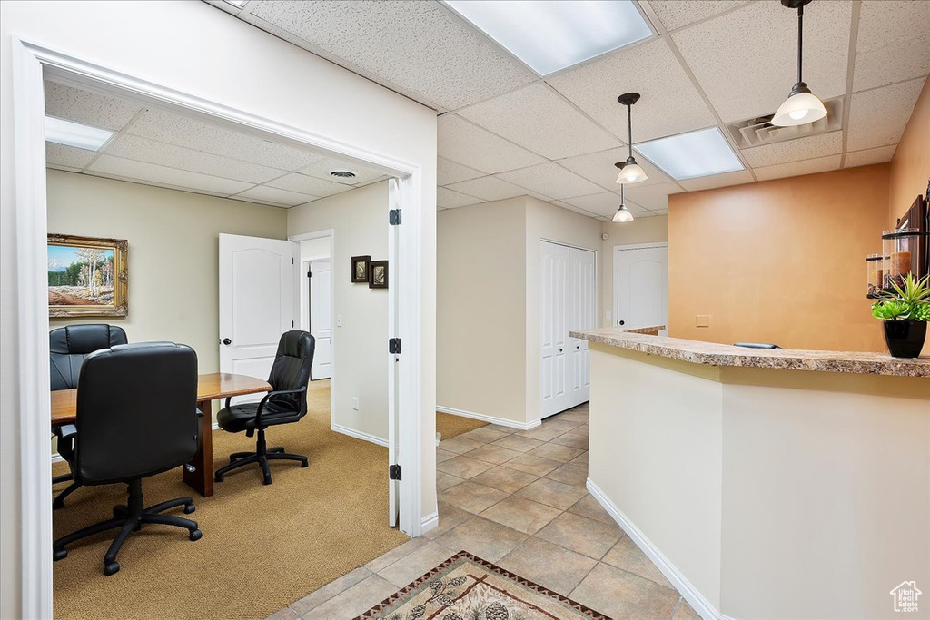 Office space with light carpet, baseboards, light tile patterned floors, and a paneled ceiling