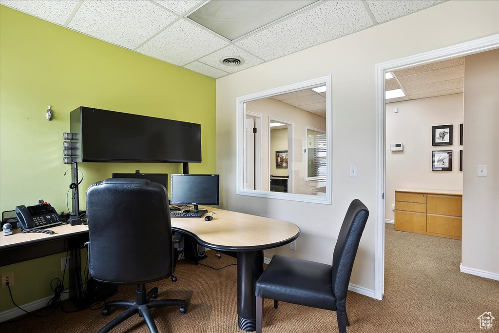 Office space with baseboards, visible vents, carpet floors, and a paneled ceiling