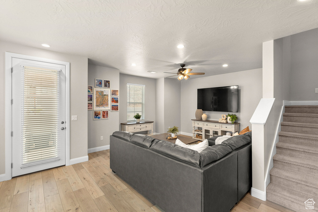 Living room featuring a ceiling fan, recessed lighting, stairway, baseboards, and light wood finished floors