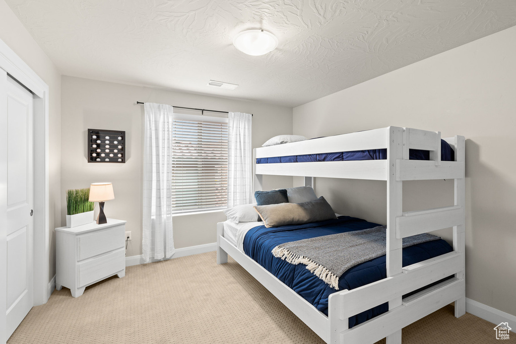 Bedroom featuring light colored carpet, baseboards, and a textured ceiling