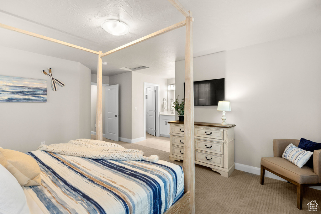 Bedroom with baseboards, light colored carpet, and connected bathroom