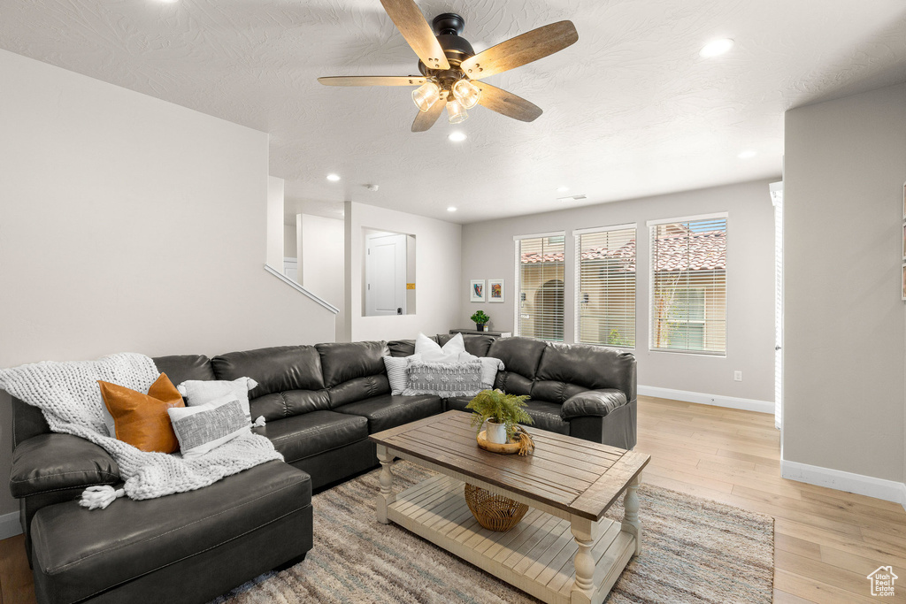 Living room with baseboards, ceiling fan, recessed lighting, and light wood-style flooring
