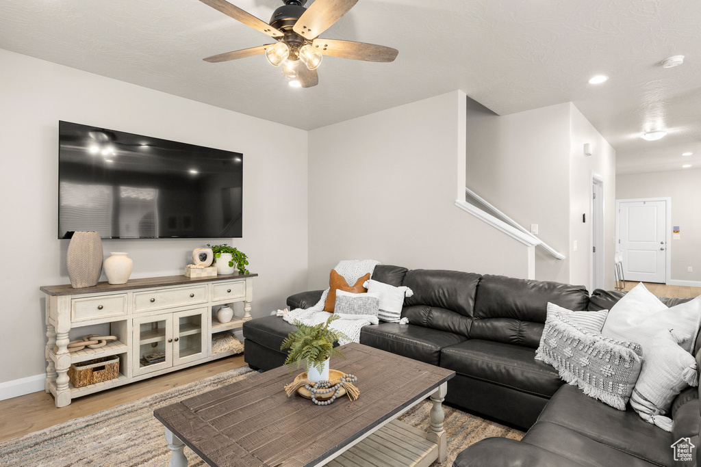 Living room featuring light wood-style flooring, ceiling fan, baseboards, and recessed lighting