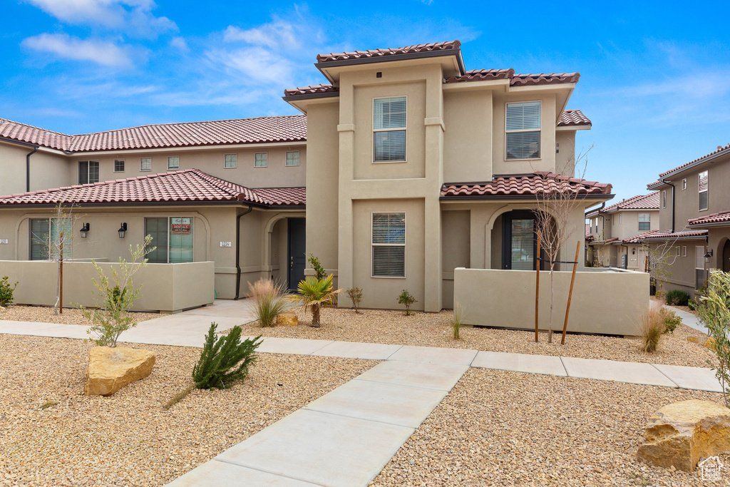 Mediterranean / spanish home featuring a tiled roof, stucco siding, and fence