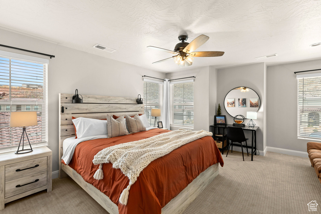 Bedroom with light carpet, baseboards, and a ceiling fan