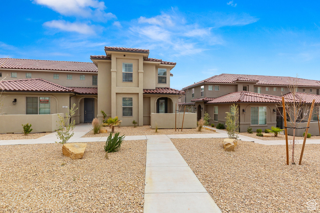 Mediterranean / spanish home with stucco siding, fence, and a tiled roof