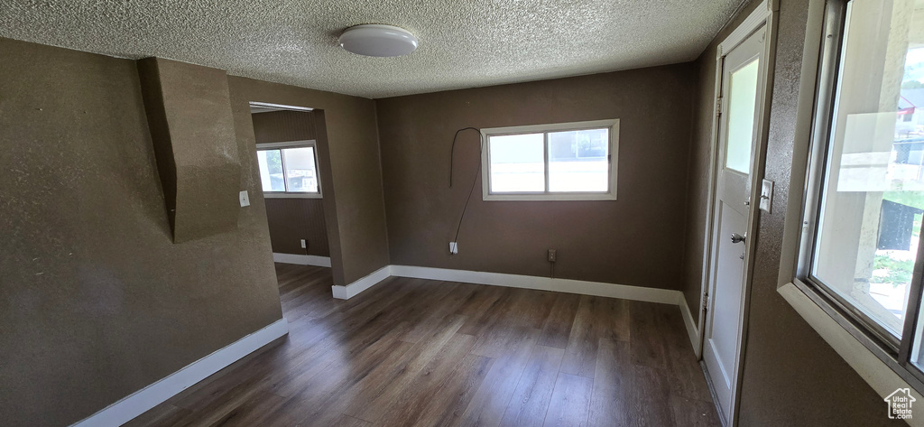 Unfurnished room with wood finished floors, baseboards, and a textured ceiling