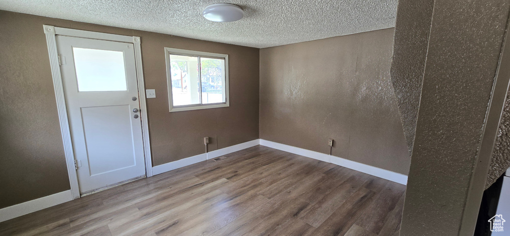 Foyer with wood finished floors, baseboards, and a textured ceiling