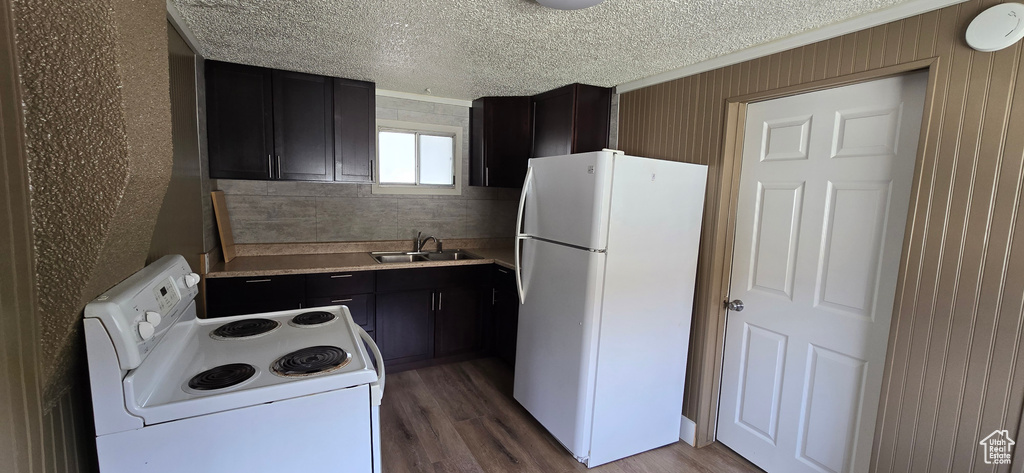Kitchen featuring white appliances, a sink, wood finished floors, light countertops, and a textured ceiling