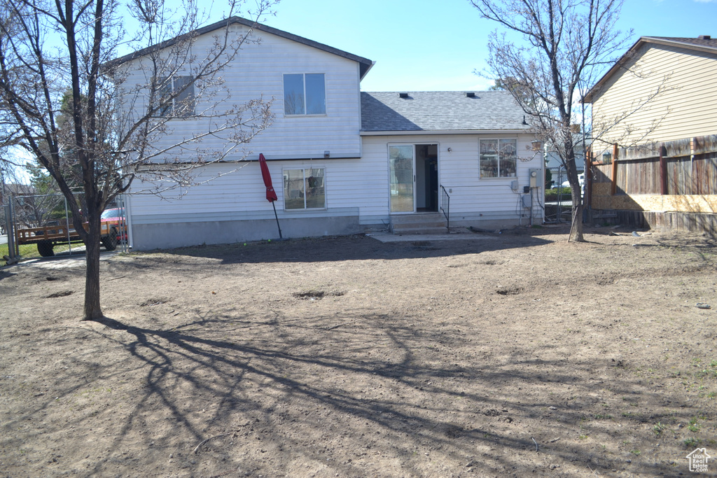Back of property with a shingled roof, fence, and entry steps