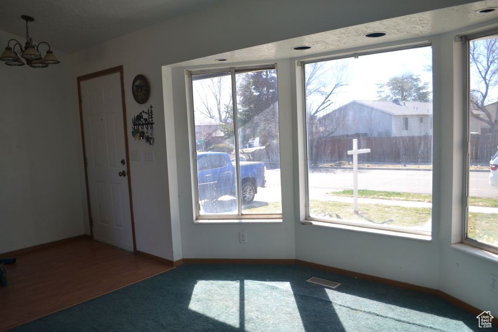 Unfurnished dining area with baseboards, visible vents, a healthy amount of sunlight, and a notable chandelier