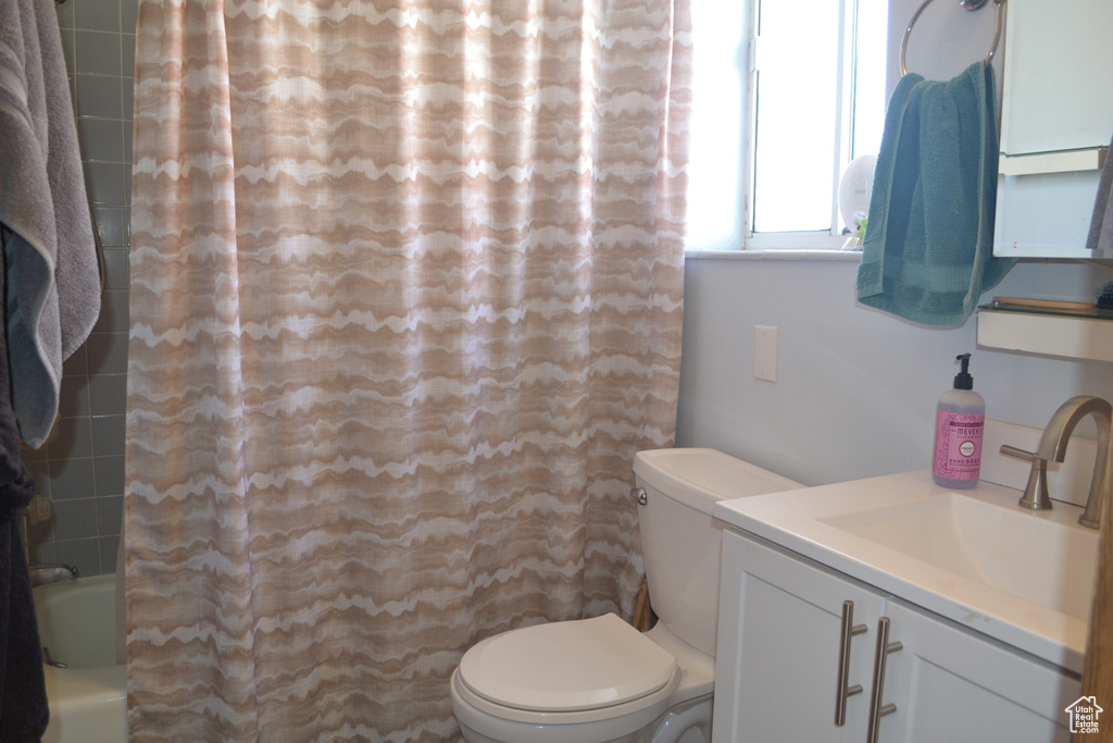 Bathroom featuring toilet, shower / tub combo with curtain, and vanity