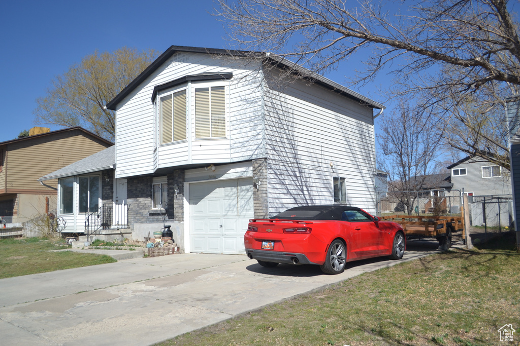 View of side of property featuring a lawn, a garage, and concrete driveway