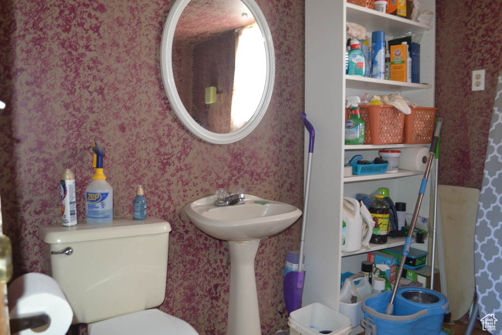 Bathroom with wallpapered walls, a sink, and toilet