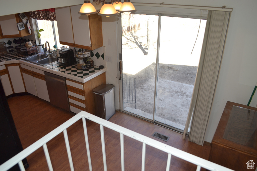Kitchen with backsplash, a sink, visible vents, dishwasher, and wood finished floors