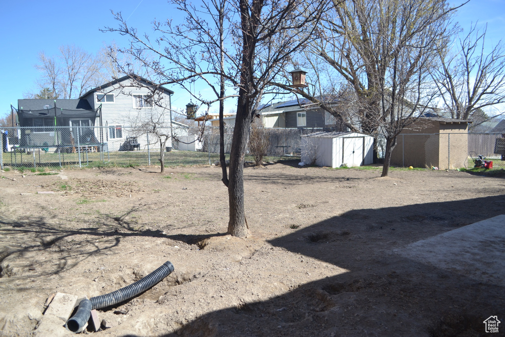 View of yard featuring an outbuilding, a shed, and fence