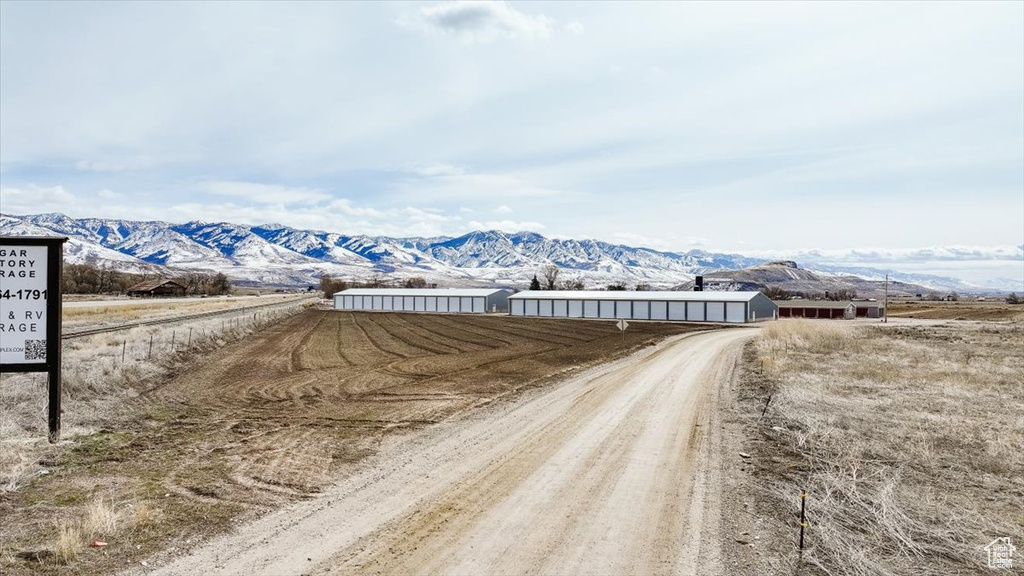 View of road featuring a rural view, a mountain view, and dirt driveway