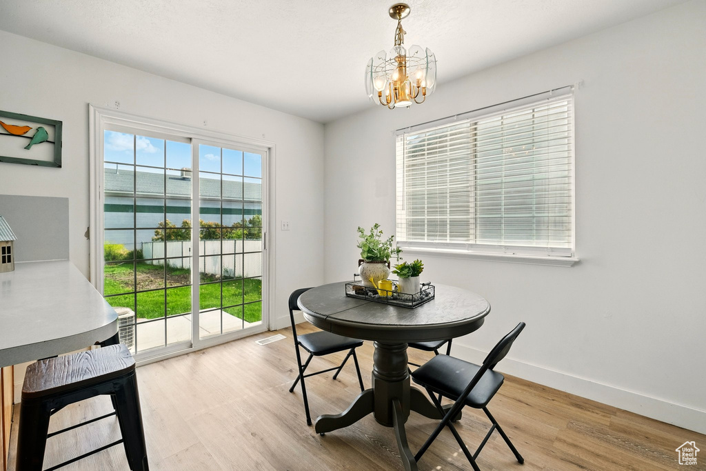 Dining space with a chandelier, wood finished floors, baseboards, and a water view