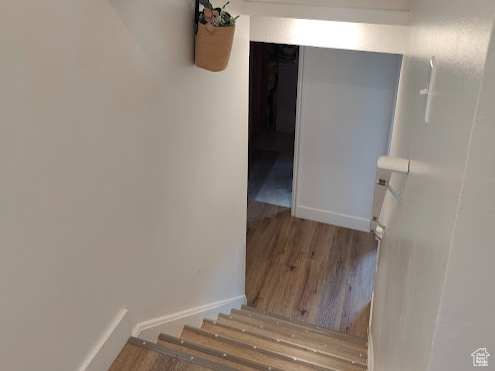 Staircase with wood finished floors, vaulted ceiling, and baseboards