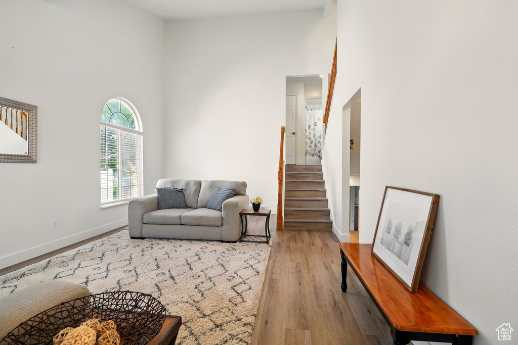 Living area with a towering ceiling, wood finished floors, baseboards, and stairway