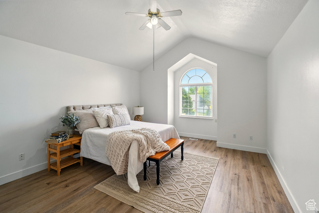 Bedroom featuring lofted ceiling, light wood finished floors, ceiling fan, and baseboards