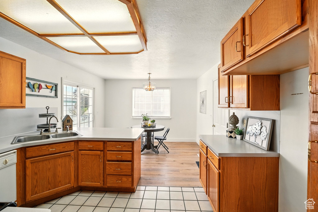 Kitchen featuring a sink, a peninsula, brown cabinetry, and plenty of natural light