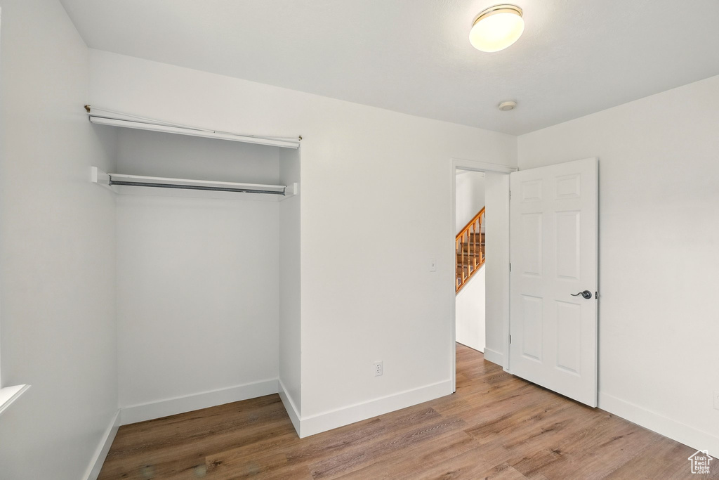 Unfurnished bedroom with wood finished floors, a closet, and baseboards