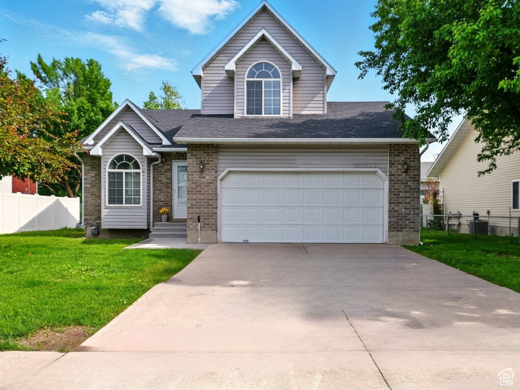 View of front facade with brick siding, driveway, an attached garage, and a shingled roof