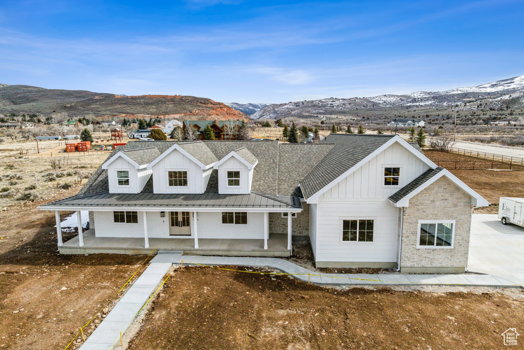 Modern farmhouse with covered porch, a mountain view, metal roof, and board and batten siding
