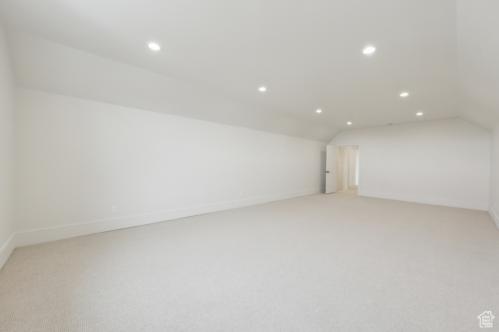 Additional living space with light colored carpet, vaulted ceiling, baseboards, and recessed lighting