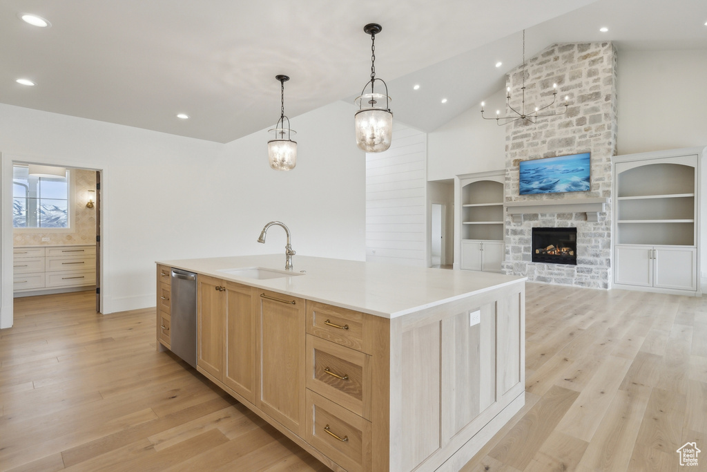 Kitchen with light wood finished floors, a sink, light brown cabinetry, and dishwasher